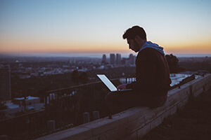 Człowiek siedzi na dachu z laptopem